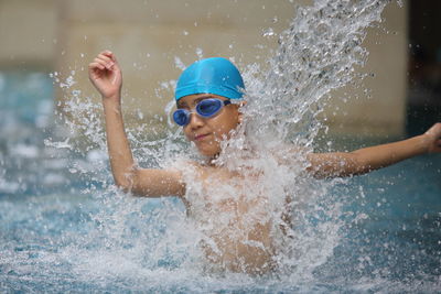 Shirtless boy splashing water in swimming pool