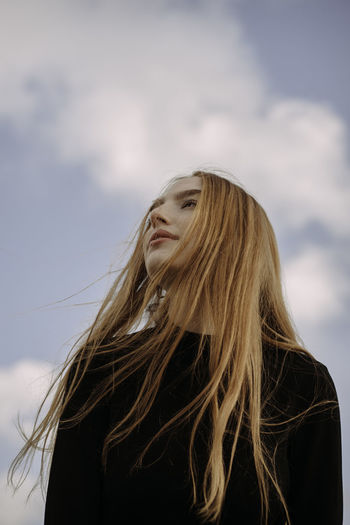 PORTRAIT OF YOUNG WOMAN AGAINST SKY WITH HAIR