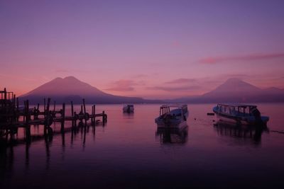 Boats moored in sea against sky during sunset