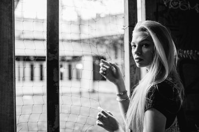 Portrait of young woman standing by window