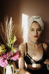 Portrait of young woman by flowers at home