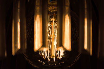 Close-up of illuminated light bulb against black background