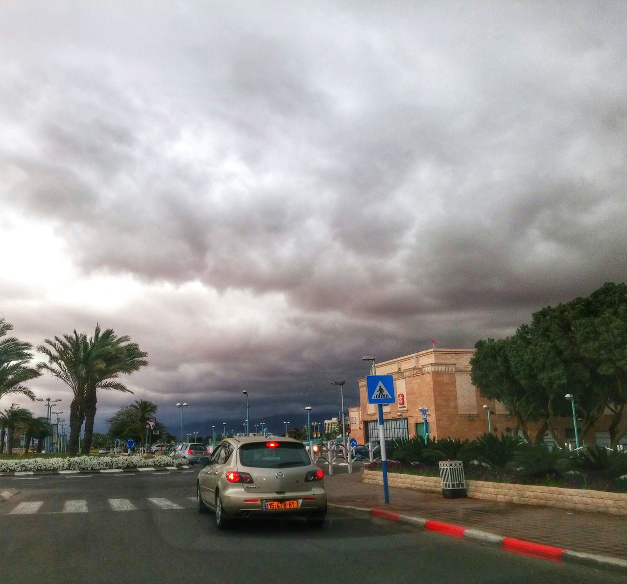 transportation, sky, cloud - sky, car, cloudy, land vehicle, road, mode of transport, architecture, building exterior, built structure, street, tree, weather, overcast, storm cloud, city, street light, cloud, on the move