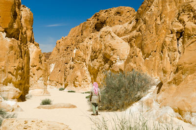 Woman standing on rock formation against mountain