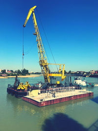 Cranes at commercial dock against clear blue sky