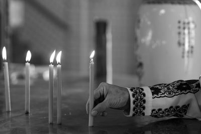 Midsection of man holding candles in temple