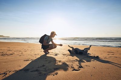 Full length of man playing with dog at beach