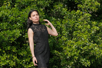 Portrait of young woman standing against plants