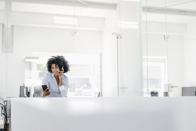 Young woman with headphones and cell phone in office