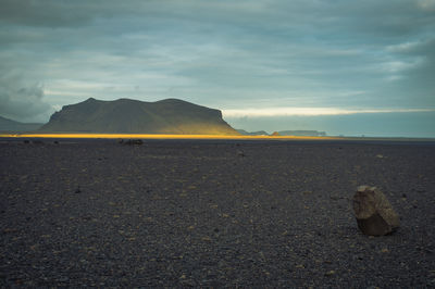 Rear view of woman standing on beach against sky