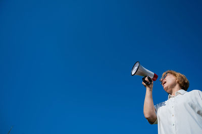 Low angle view of man standing against blue sky