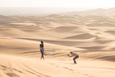 Man photographing woman standing at desert