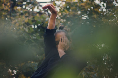 Thoughtful young man dancing against trees 