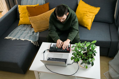 Midsection of woman using laptop on sofa at home