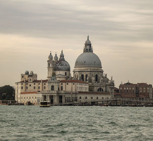 View of buildings at waterfront against cloudy sky