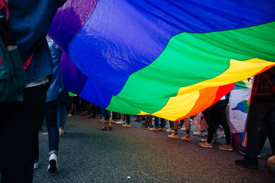 Low section of people walking at multi colored umbrellas