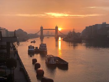 Bridge over river in city during sunset