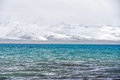 Scenic view of sea and snowcapped mountains against sky