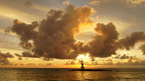 Silhouette people on sea against sky during sunset