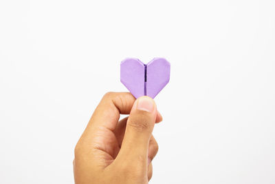 Close-up of hand holding heart shape over white background