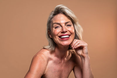 Portrait of shirtless young woman against pink background