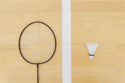 Close-up of shuttlecock and badminton on hardwood floor