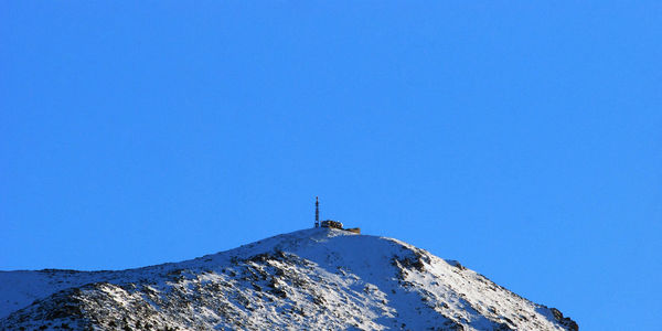 Low angle view of cross on mountain against blue sky