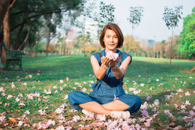 Portrait of smiling young woman sitting on field at park