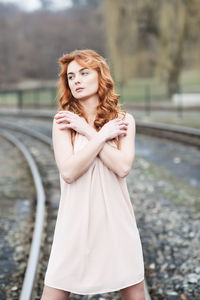 Portrait of young woman looking away while standing outdoors