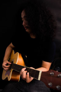 Man playing guitar over black background