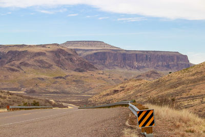 Scenic view of road by mountains against sky