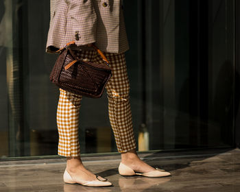 Low section of woman standing while holding bag