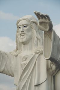 Standing majestic jesus statue blessing with both the hands against blue sky background.