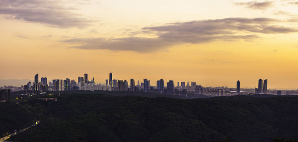 Modern buildings in city against sky during sunset