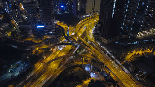 High angle view of illuminated street amidst buildings in city at night