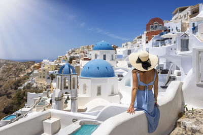 Rear view of woman wearing hat looking at townscape