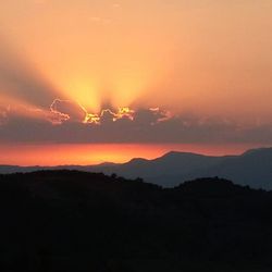 Scenic view of silhouette mountains against romantic sky at sunset