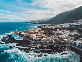 Aerial view of sea and buildings against sky