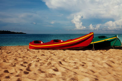 Deck chairs on beach against sky