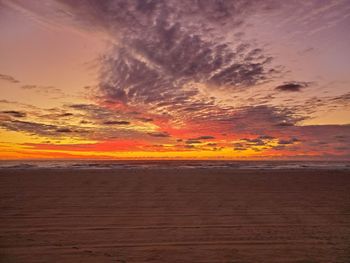 Scenic view of sea against dramatic sky during sunset