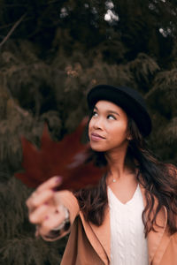 Beautiful young woman holding dry maple leaf