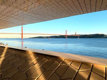 View of suspension bridge over sea against clear blue sky