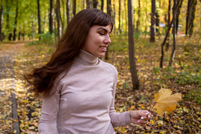 Portrait of young woman standing against trees in forest