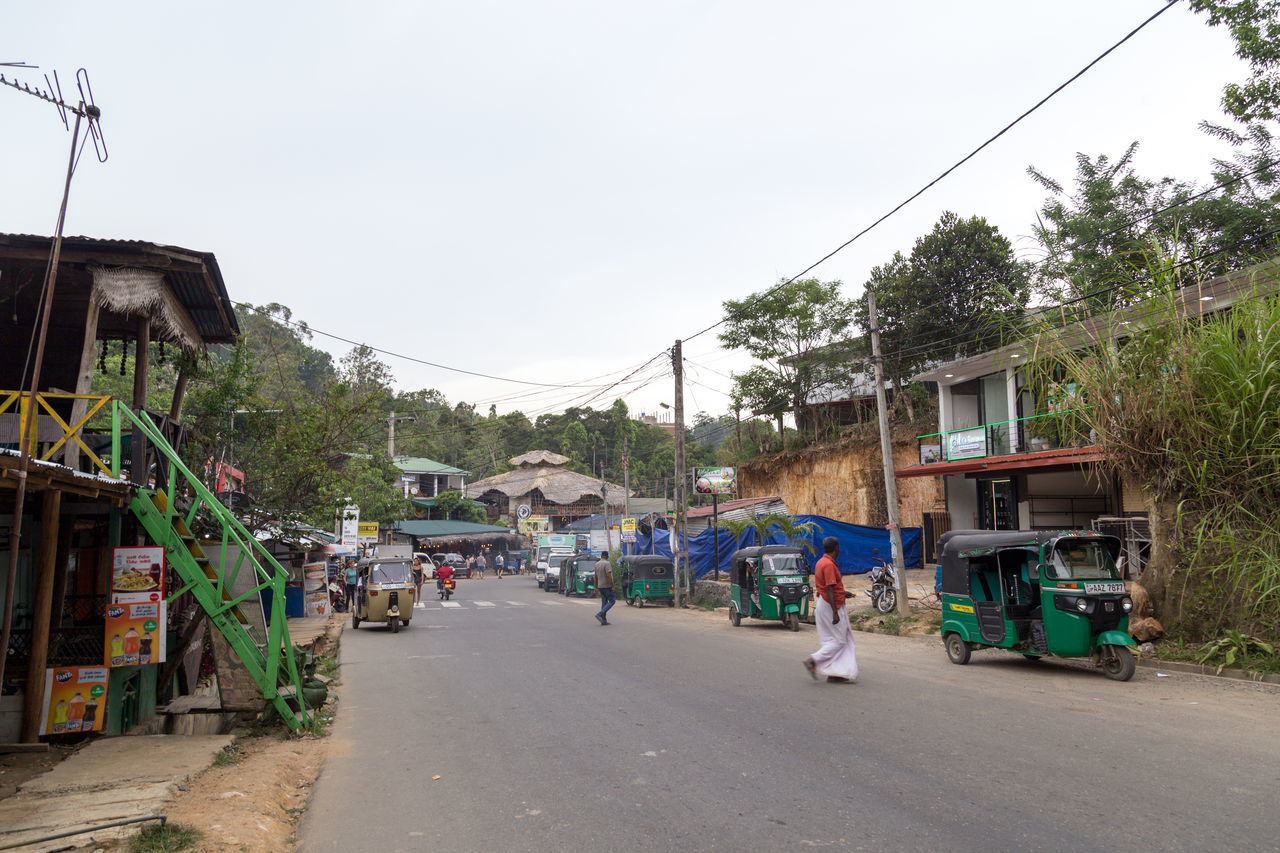 CARS ON STREET BY HOUSES AGAINST SKY