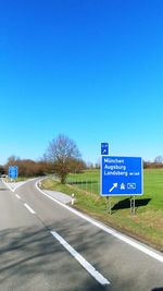 Information sign by road against blue sky