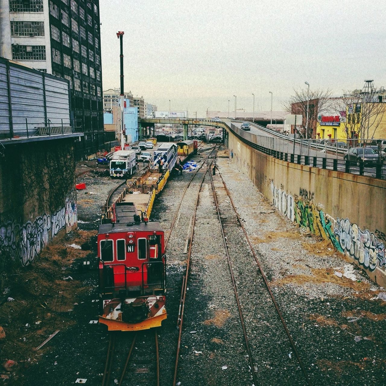 transportation, building exterior, architecture, built structure, mode of transport, railroad track, land vehicle, city, car, street, public transportation, rail transportation, the way forward, sky, diminishing perspective, high angle view, day, outdoors, building, train - vehicle