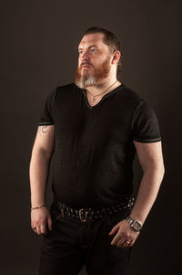 Young man standing against black background