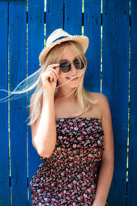 Portrait of smiling teenager standing by wooden wall outdoors