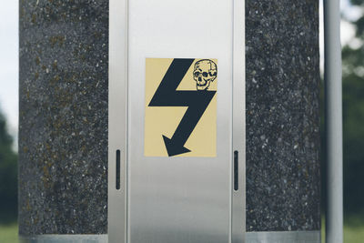 Close-up of danger sign with human skull on electric pole