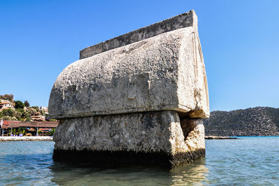 Built structure by sea against clear blue sky